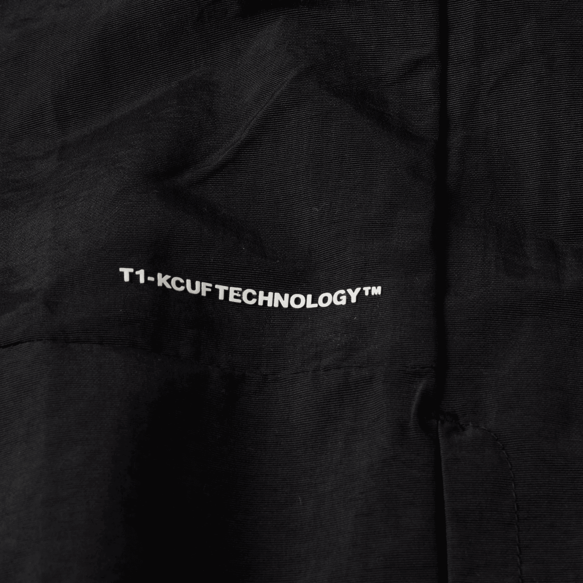 Black HUF All Caps Shell Jacket with hood, front zipper, and adjustable cuffs, designed for outdoor wear and style.