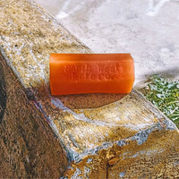 Orange skateboard wax by South West Skate Co, shown in a container with the wax visible inside.