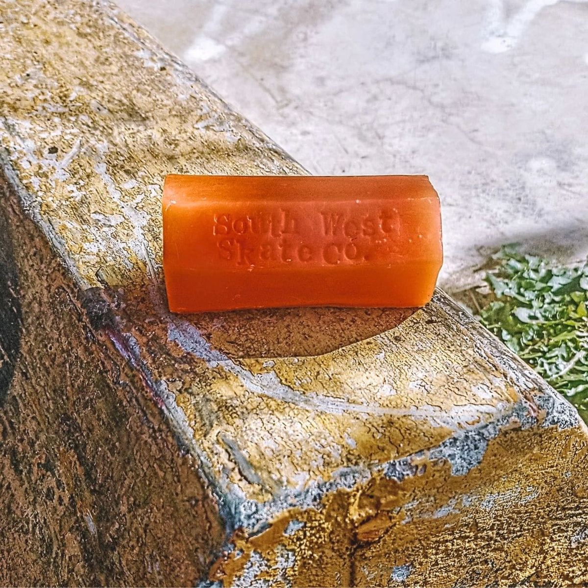 Orange skateboard wax by South West Skate Co, shown in a container with the wax visible inside.