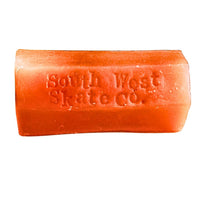 Orange skateboard wax from South West Skate Co for grip and maintenance, shown in a close-up of the wax block.
