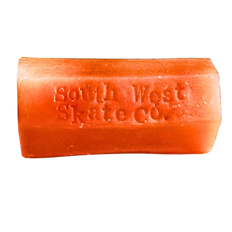 Orange skateboard wax from South West Skate Co for grip and maintenance, shown in a close-up of the wax block.